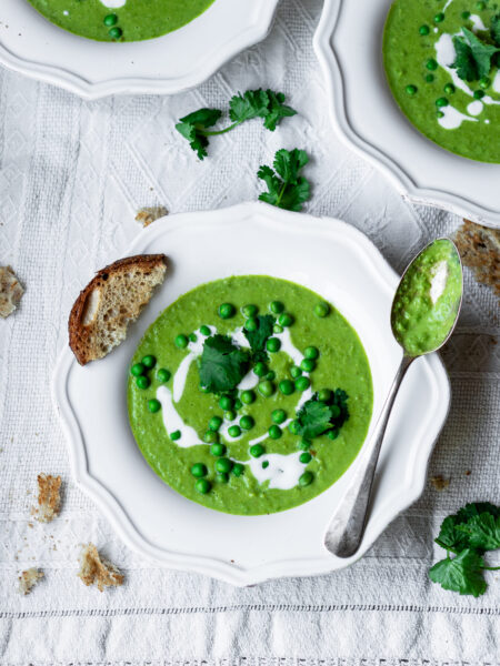 Creamy green pea soup served with fresh herbs and a drizzle of cream.