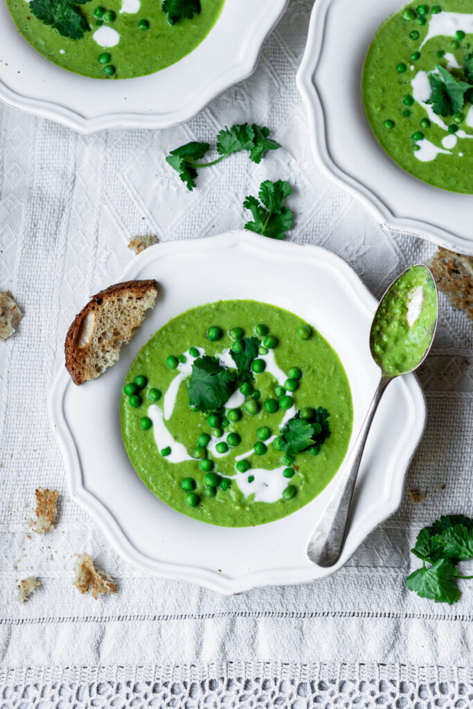 Creamy green pea soup served with fresh herbs and a drizzle of cream.